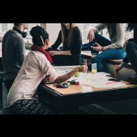 Photo montrant quelques jeunes personnes autour d'une table, en situation de collaboration